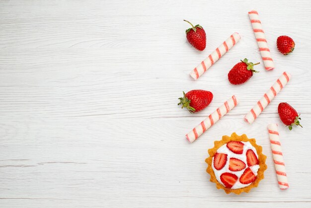 Draufsicht kleiner cremiger Kuchen mit frischen Erdbeeren und Süßigkeiten auf dem hellen Hintergrundkuchen süßes Foto Fruchtbeeren backen