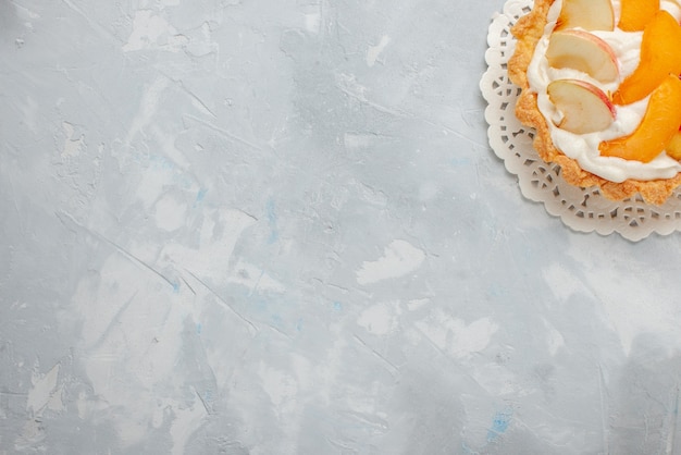 Draufsicht kleiner cremiger Kuchen mit geschnittenen Früchten auf dem süßen Kekskeks des weißen Schreibtischfruchtkuchens