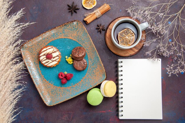 Draufsicht kleiner cremiger Kuchen mit Schokoladenkeksen und Tasse Tee auf dem dunklen Oberflächenkekskuchen süßer Kuchenzuckerkeks