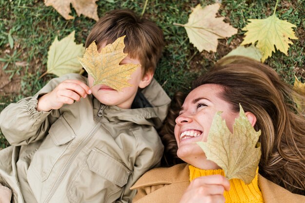 Draufsicht kleiner Junge und Mutter spielen mit Herbstlaub