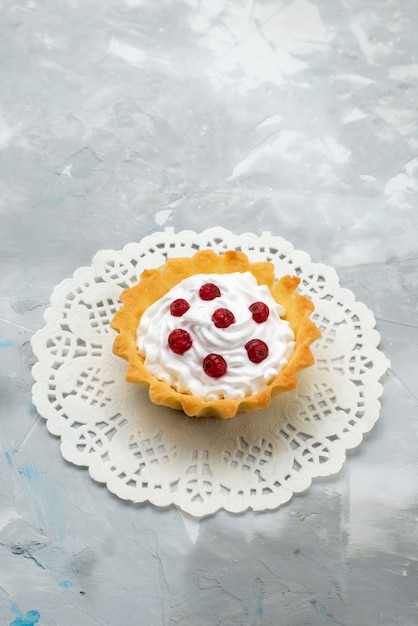 Draufsicht kleiner köstlicher Kuchen mit Sahne und roten Früchten auf der grauen Oberfläche süß