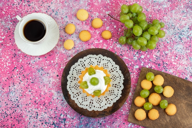 Draufsicht kleiner Kuchen mit Sahne Tasse Tee Kekse und zusammen mit grünen Trauben auf der hellen Oberfläche Kuchenfrucht