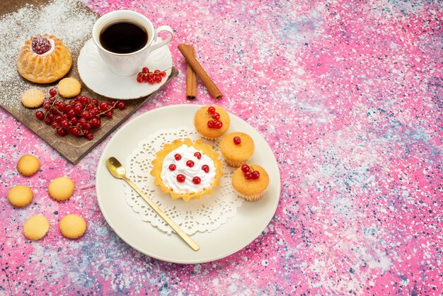 Draufsicht kleiner Kuchen mit Sahnekeksen frische Preiselbeeren zusammen mit Tasse Kaffee und Zimt auf den farbigen Oberflächenkeksen