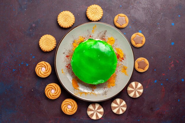 Draufsicht kleiner leckerer Kuchen mit verschiedenen Keksen auf der dunklen Oberfläche