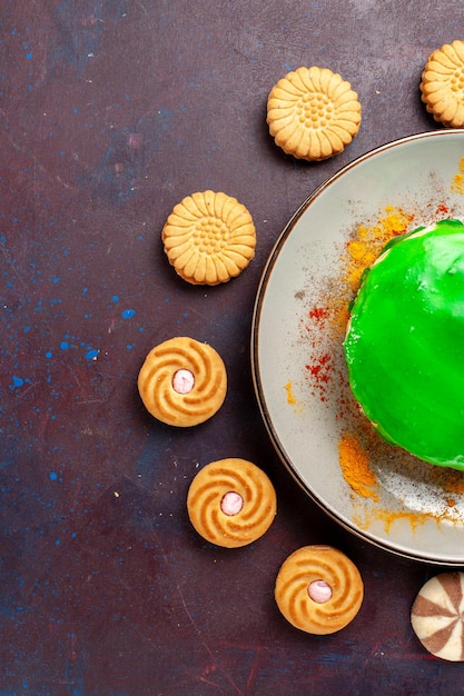 Draufsicht kleiner leckerer kuchen mit verschiedenen kleinen keksen auf dunkler oberfläche