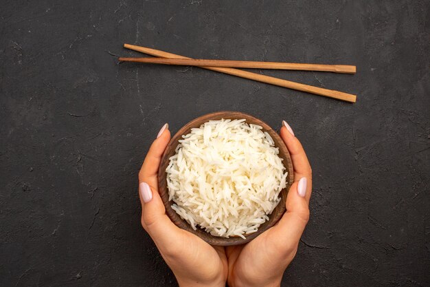 Draufsicht köstlich gekochter Reis einfache leckere Mahlzeit im Teller auf dem dunklen Raum