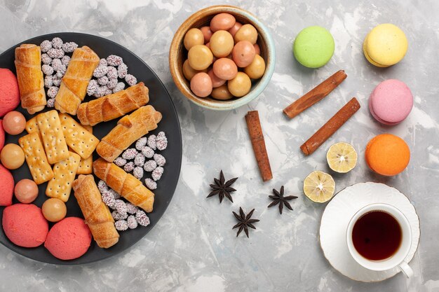 Draufsicht köstliche Bagels mit Crackern Zimt und Macarons auf dem weißen Schreibtischkuchenkeks süßer Zuckerkuchenplätzchen knusprig