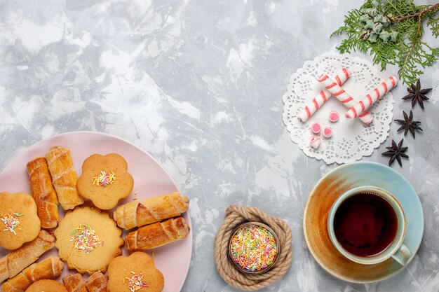 Draufsicht köstliche Bagels mit Kuchen und Tee auf weißem Schreibtisch