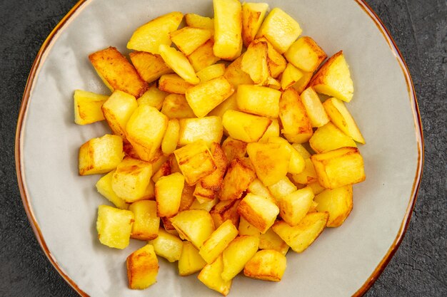 Draufsicht köstliche Bratkartoffeln innerhalb des Tellers auf dunklem Hintergrund