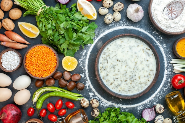 Draufsicht köstliche Dovga in Holzschale Koriander Kirschtomaten Wachteleier Knoblauch Walnuss Kastanie auf dem Tisch