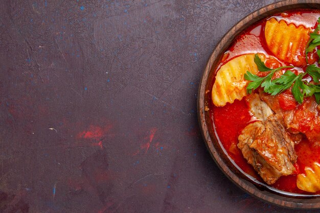 Draufsicht köstliche Fleischsoßensuppe mit Grüns und in Scheiben geschnittenen Kartoffeln auf dunkler Oberflächensoßen-Suppe-Mahlzeit-Abendessen-Gericht