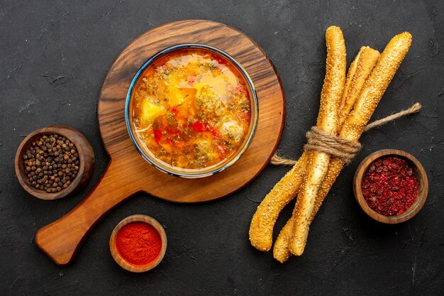 Draufsicht köstliche Fleischsuppe mit Brot und Gewürzen auf der Grauzone