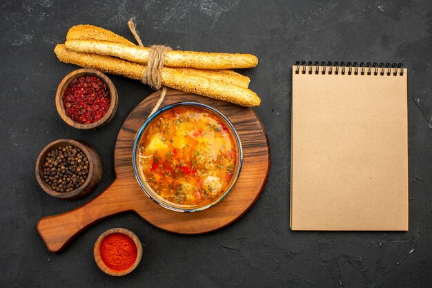 Draufsicht köstliche Fleischsuppe mit Brot und Gewürzen auf der Grauzone