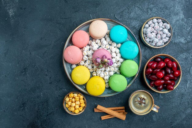 Draufsicht köstliche französische macarons mit bonbons und hartriegel auf dunklem raum