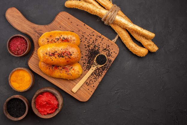 Draufsicht köstliche gebackene Pastetchen mit verschiedenen Gewürzen auf dem grauen Hintergrund Fleischpastete Gebäckkuchen backen Ofen