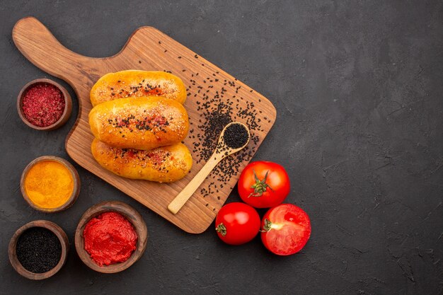 Draufsicht köstliche gebackene Pastetchen mit verschiedenen Gewürzen und Tomaten auf grauem Hintergrund Fleischpastete Gebäckkuchen backen Ofen