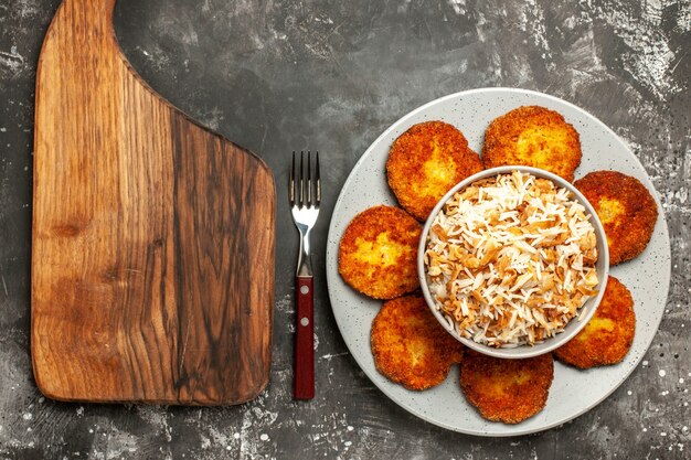 Draufsicht köstliche gebratene Schnitzel mit gekochtem Reis auf dunklem Frikadellengericht