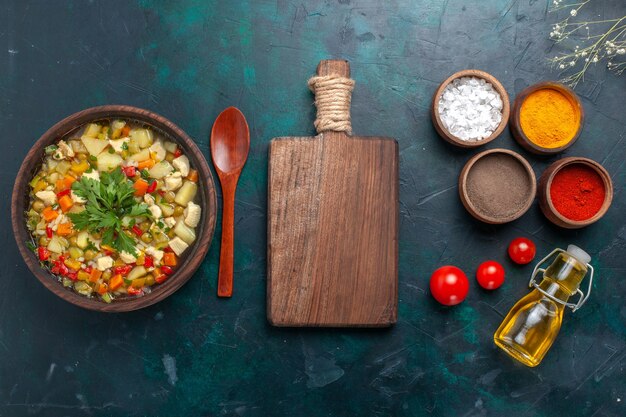 Draufsicht köstliche Gemüsesuppe mit Öl und verschiedenen Gewürzen auf dunklem Schreibtisch Zutat Gemüsesuppe Salatöl