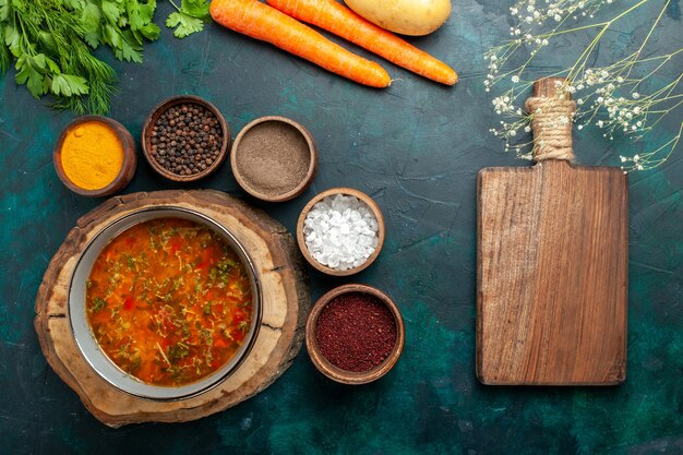 Draufsicht köstliche Gemüsesuppe mit verschiedenen Gewürzen auf dunkelgrüner Oberfläche Lebensmittelgemüse Zutaten Suppe Produkt Mahlzeit