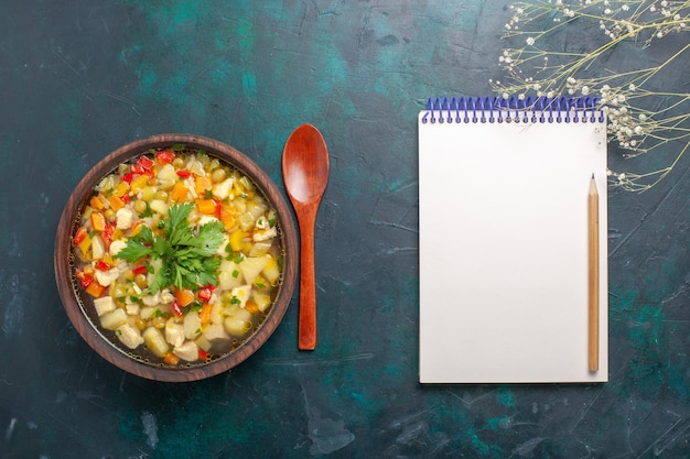 Draufsicht köstliche gemüsesuppe mit verschiedenen zutaten und notizblock auf dem dunklen schreibtisch suppe gemüsesauce essen warmes essen mahlzeit