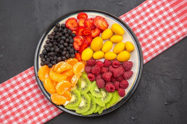 Draufsicht köstliche geschnittene Früchte im Teller auf dunklem Foto ausgereifter Obstbaum exotisches reifes gesundes Leben