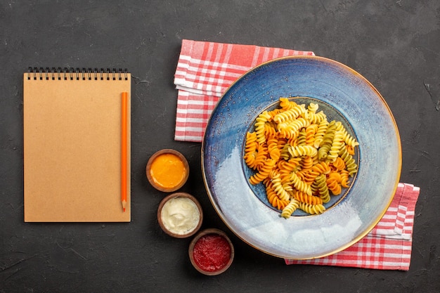 Draufsicht köstliche italienische Pasta ungewöhnliche gekochte Spiralnudeln auf dem dunklen Hintergrund Nudelgericht Mahlzeit kochen Abendessen