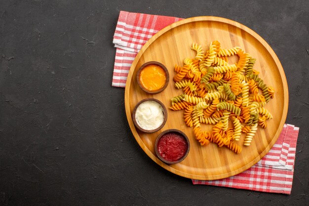 Draufsicht köstliche italienische Pasta ungewöhnliche gekochte Spiralnudeln auf dunklem Hintergrundgericht, das Pasta-Abendessen kocht?