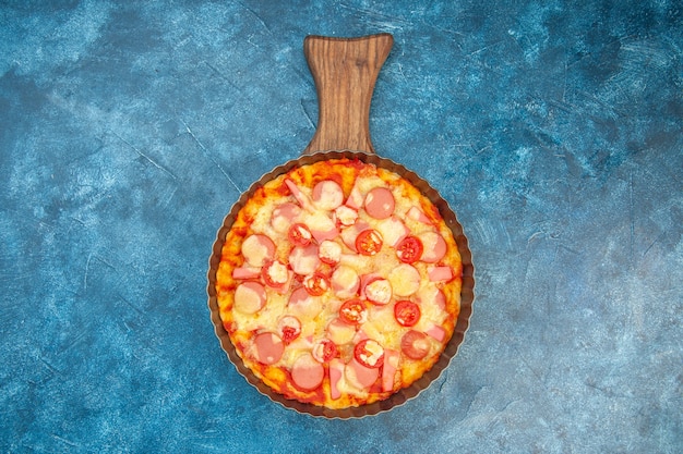 Draufsicht köstliche Käsepizza mit Würstchen und Tomaten auf blauem Hintergrund Lebensmittelteigkuchenfarbe fast-food italienisches Foto