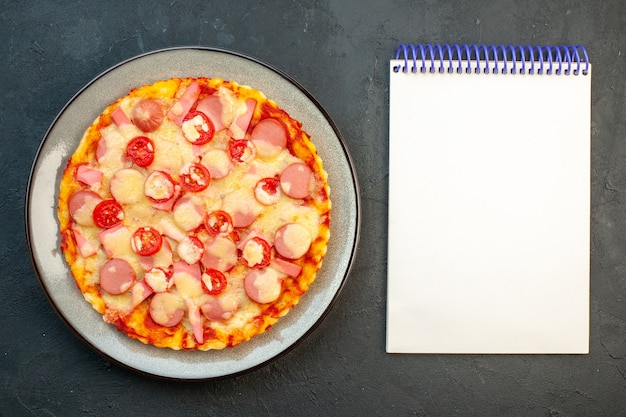 Kostenloses Foto draufsicht köstliche käsepizza mit würstchen und tomaten auf dunklem hintergrund italienischer lebensmittelteig-fast-food-fotofarbe