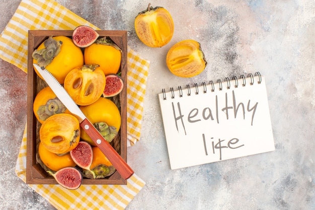 Draufsicht köstliche Kaki und geschnittene Feigen in Holzkiste gelbes Küchentuch gesundes Leben auf Notebook geschrieben