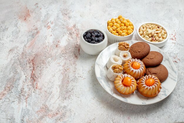 Draufsicht köstliche Kekse mit Bonbons und Nüssen auf weißem Hintergrund süße Kuchenkekse Keksnuss