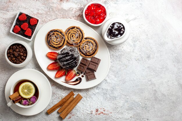 Draufsicht köstliche Kekse mit Schokoladenkuchen und Tee auf hellem Raum