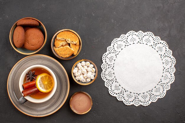 Draufsicht köstliche Kekse mit Tasse Tee auf dunkler Oberfläche Zuckerkeks Dessert Keks süß