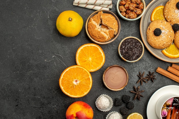 Kostenloses Foto draufsicht köstliche kekse mit tasse tee und orangenscheiben auf dunklem teeplätzchen-kekskuchen