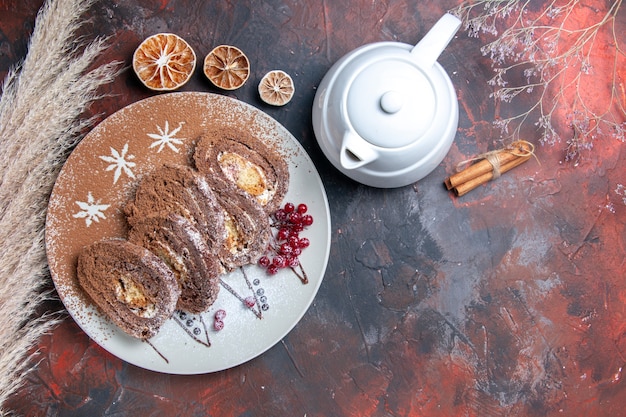 Draufsicht köstliche Keksröllchen geschnittene cremige Kuchen auf dunklem Boden