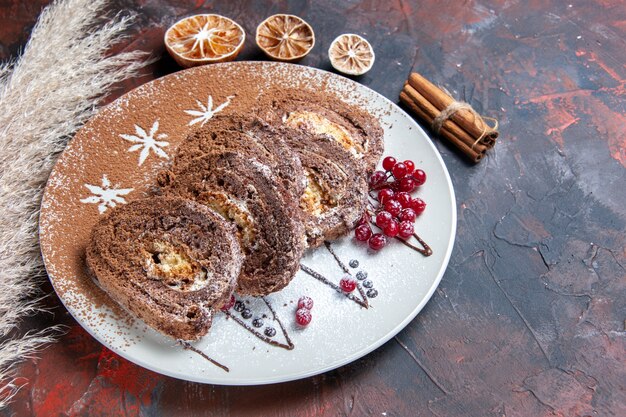 Kostenloses Foto draufsicht köstliche keksröllchen geschnittene cremige kuchen auf dunklem tischkuchenkuchen süß