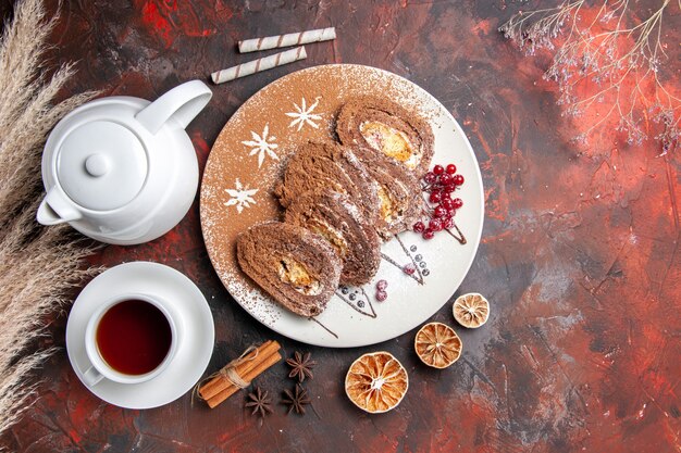 Draufsicht köstliche Keksröllchen mit Tasse Tee auf dunklem Tisch