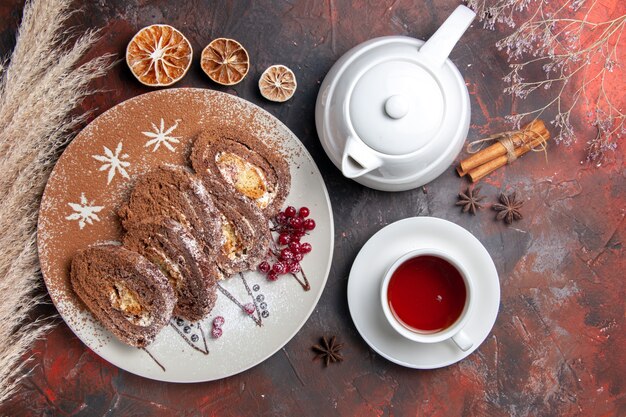 Draufsicht köstliche Keksröllchen mit Tasse Tee auf dunklem Tischkuchenkuchen süß