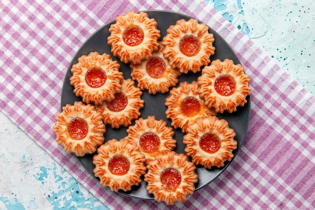 Draufsicht köstliche kleine kekse mit orangenmarmelade auf dem blauen schreibtischkekskeks süßer zuckerfarbentee