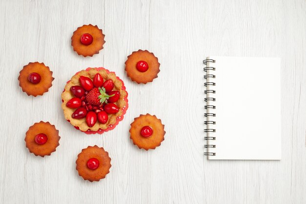 Draufsicht köstliche kleine Kuchen mit Früchten auf weißem Schreibtisch