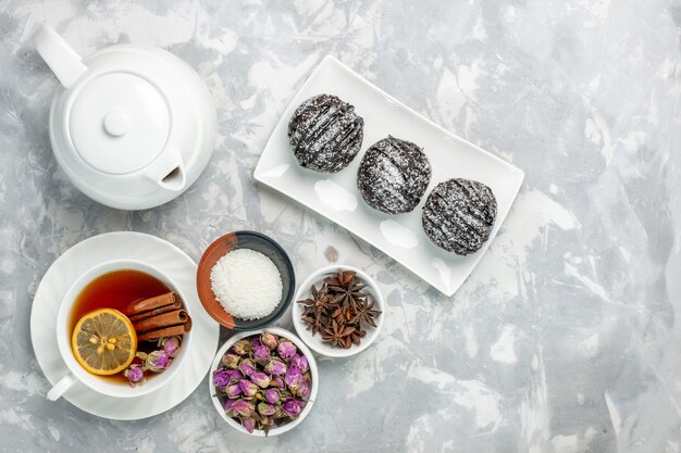 Draufsicht köstliche kleine Kuchen mit Zuckerguss und Tasse Tee auf hellweißem Hintergrund Teekekskuchen Zucker süße Kuchenplätzchen