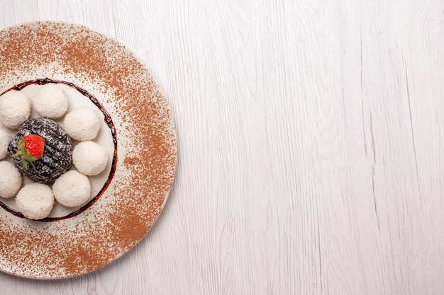 Draufsicht köstliche Kokosbonbons mit Schokoladenkuchen auf dem weißen Schreibtisch Zuckerkuchenkeks süße Süßigkeitenkekse can