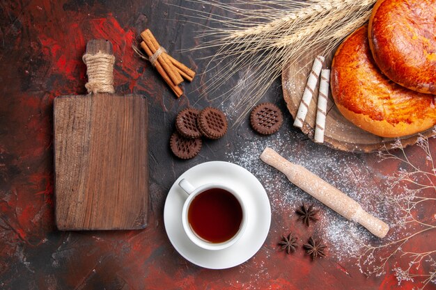 Draufsicht köstliche Kuchen für Tasse Tee auf dem dunklen Tisch