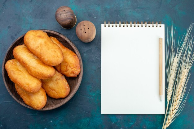 Draufsicht köstliche Kuchen mit Fleischfüllung in Holzplatte auf dunkelblauem Schreibtisch Teigkuchen Brötchen Essen