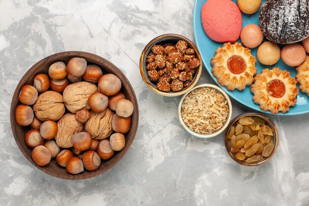 Draufsicht köstliche Kuchen mit Macarons Nüssen und Keksen auf der weißen Oberfläche