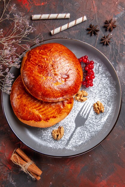 Draufsicht köstliche Kuchen mit roten Beeren auf dem dunklen Tisch süßer Kuchen Gebäckkuchen