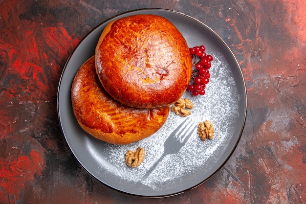 Draufsicht köstliche Kuchen mit roten Beeren auf dem dunklen Tisch süßer Kuchen Gebäckkuchen