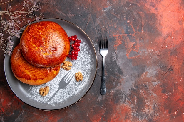 Draufsicht köstliche Kuchen mit roten Beeren auf dem dunklen Tischkuchen süßer Gebäckkuchen