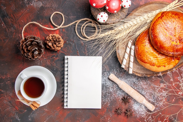 Draufsicht köstliche Kuchen mit Tasse Tee auf dem dunklen Tisch süßer Kuchen Gebäckkuchen