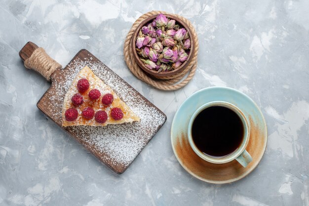 Draufsicht köstliche Kuchenscheibe mit Tasse Tee auf dem leichten Schreibtischkuchenkeks süßer Zuckerauflauf